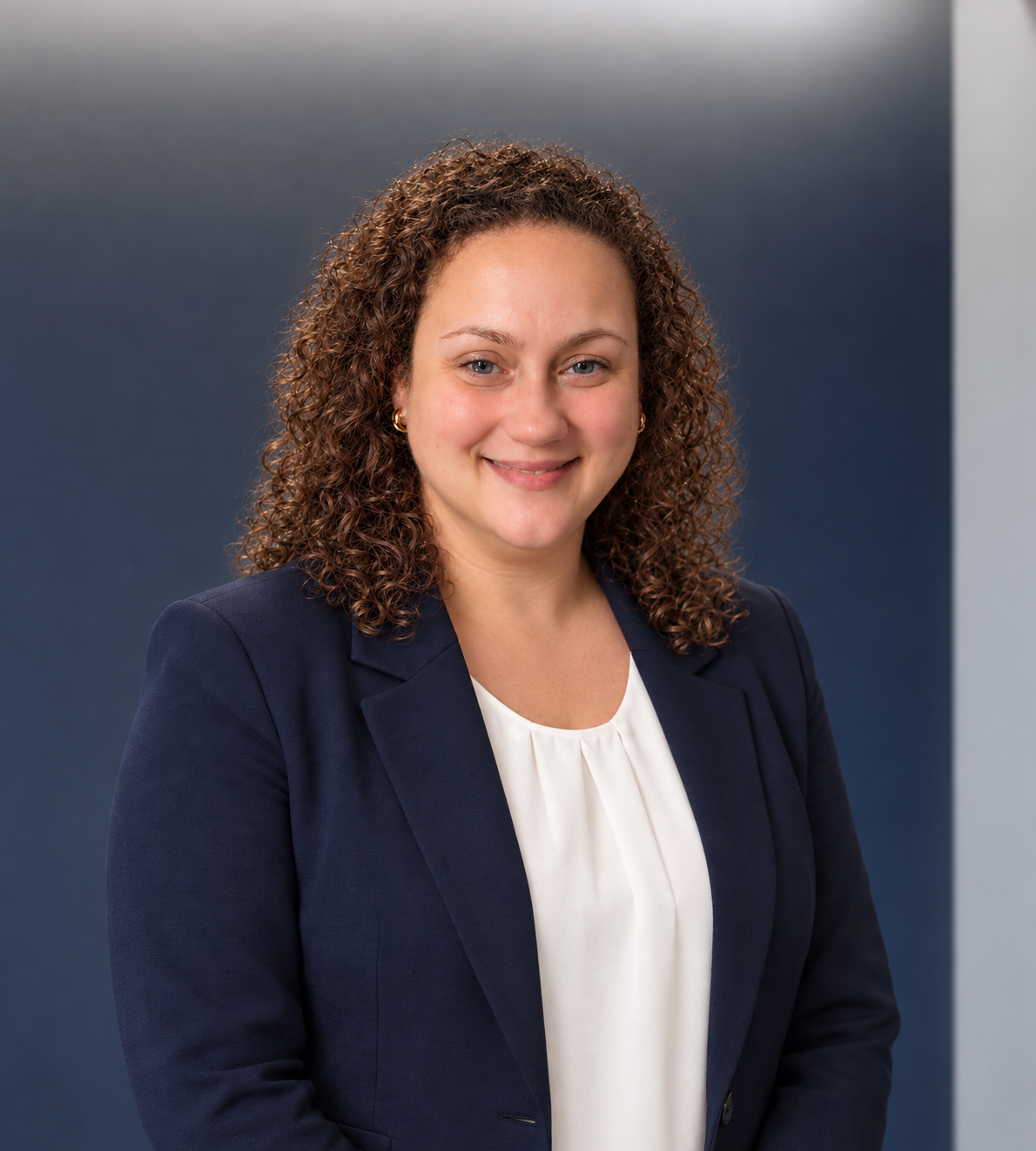 Sarah Lafarge smiling in a navy blazer and white blouse against a navy office backdrop